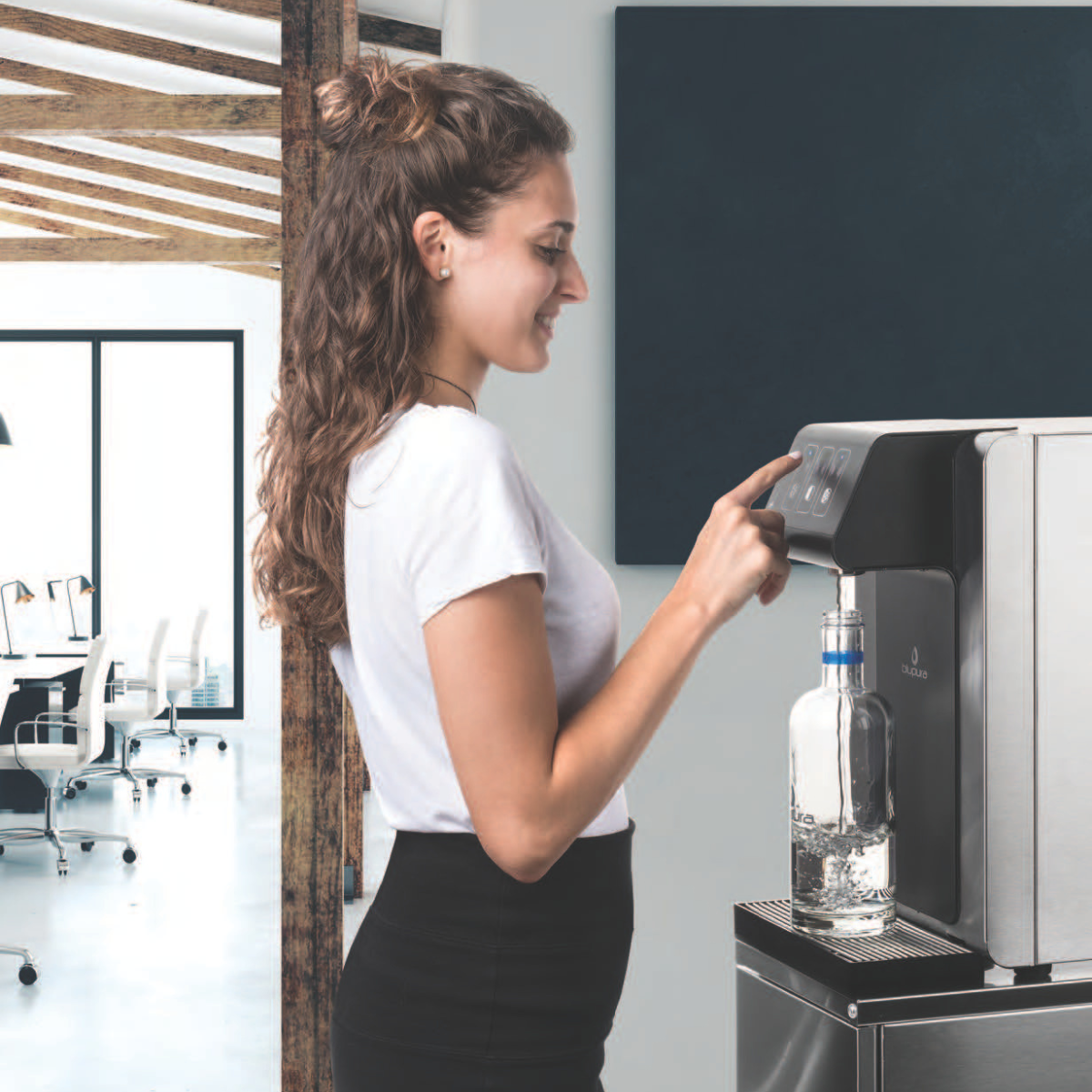 Eine Frau füllt konzentriert eine Glasflasche an einem modernen Wasserspender in einem Büro.